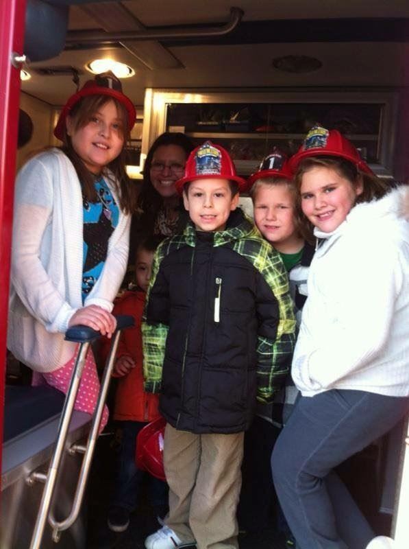 Children in red plastic firemens' hats at a public education event